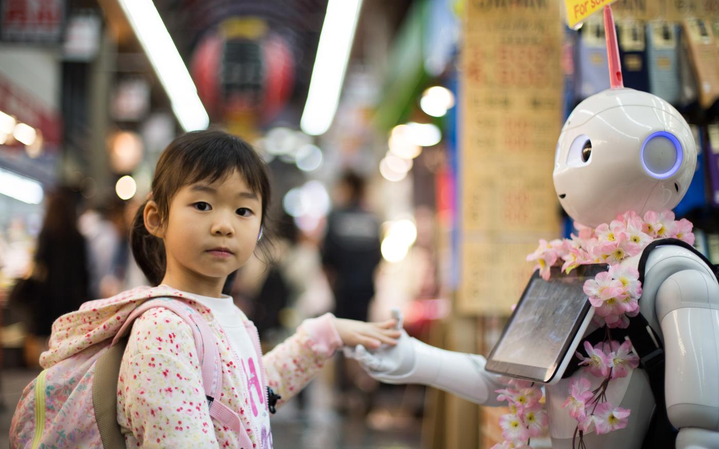 photo of girl laying left hand on white digital robot by Andy Kelly courtesy of Unsplash.