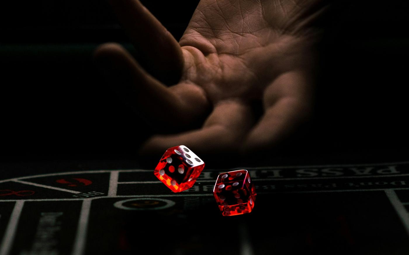 a hand with a finger pointing at a red and white dice by Leon-Pascal Jc courtesy of Unsplash.