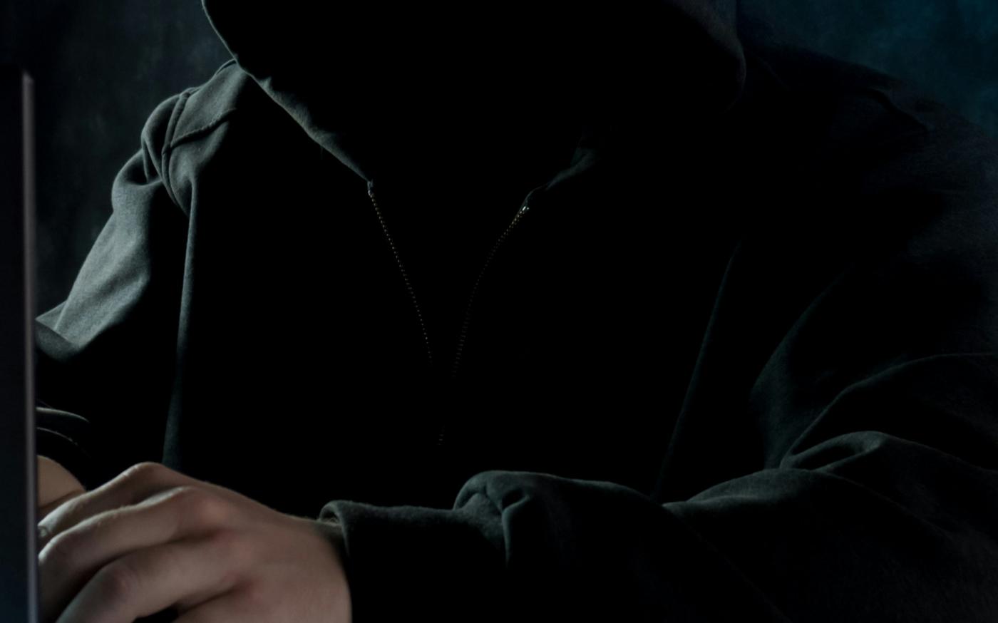a man in a hoodie using a laptop computer by Bermix Studio courtesy of Unsplash.