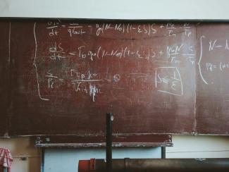 written equations on brown wooden board by Roman Mager courtesy of Unsplash.