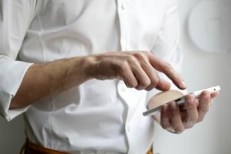 person holding white Android smartphone in white shirt by NordWood Themes courtesy of Unsplash.