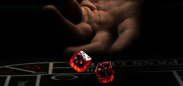 a hand with a finger pointing at a red and white dice by Leon-Pascal Jc courtesy of Unsplash.