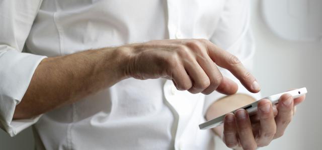 person holding white Android smartphone in white shirt by NordWood Themes courtesy of Unsplash.
